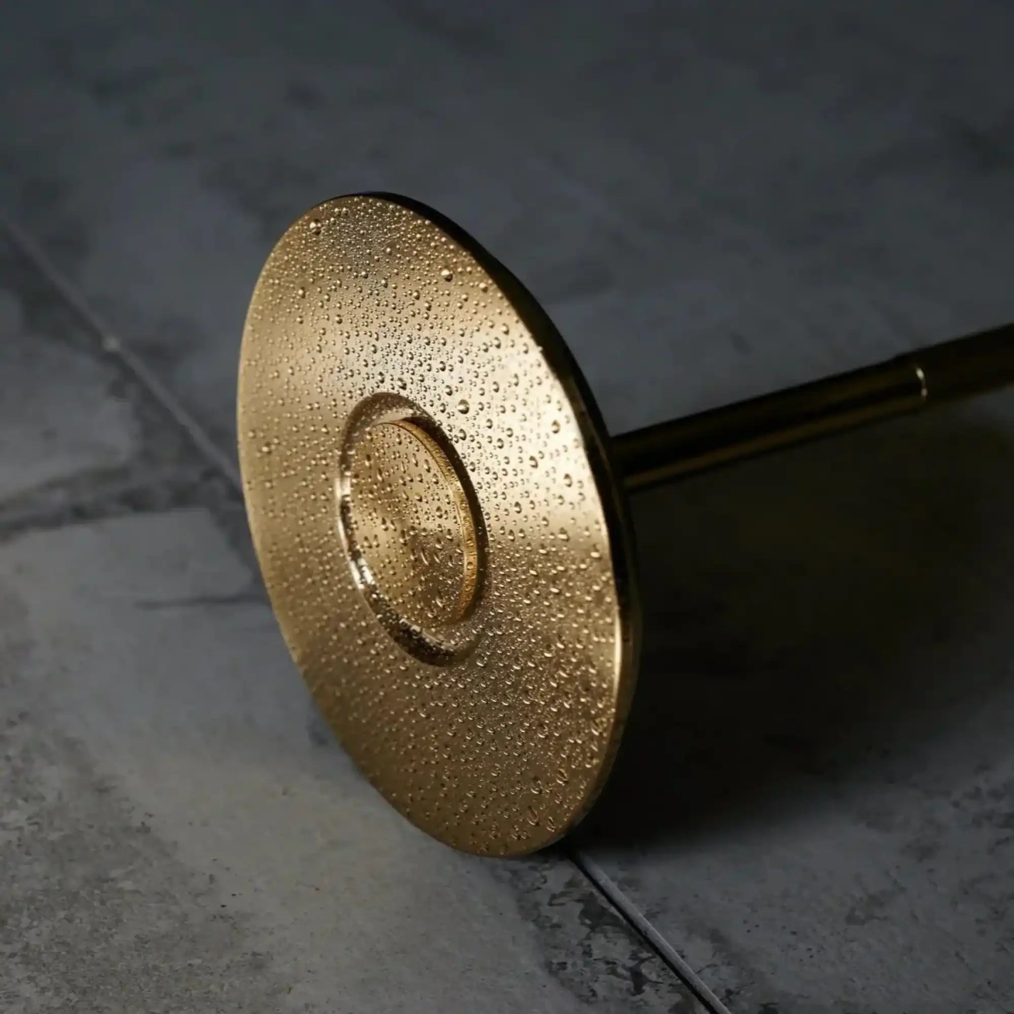 golden-colored-circular-shower-head-water-droplets-surface.webp
