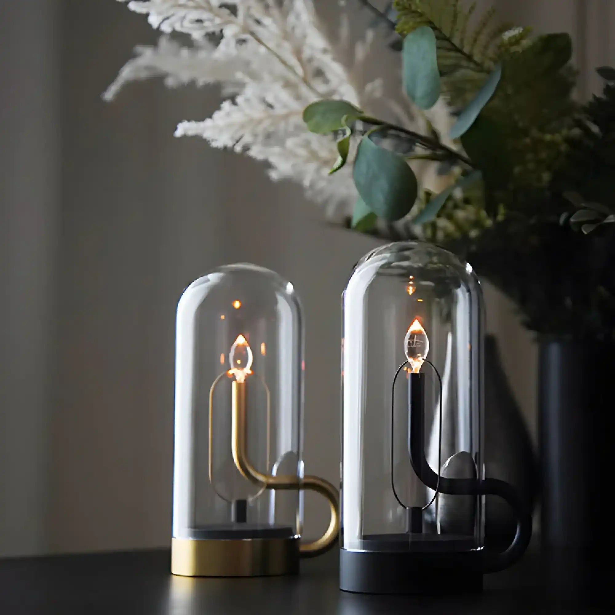 two-modern-battery-powered-led-lamps-candle-like-flames-brass-base-black-enclosed-clear-glass-domes.webp